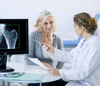 Врач показывает пациентке снимок на экране компьютера